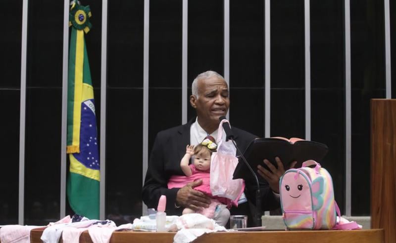Deputado Pastor Isidório (Avante-BA) em plenário acompanhado de uma boneca e a Bíblia.