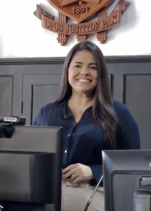 Na fotografia aparece uma mulher, de blusa azul, em frente à mesa do tribunal