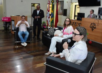 -Imagem de Capilé com calça jeans e camisa rosa, ao lado Nalva Coutinho e Renata Gregório, ambas de paletó branco