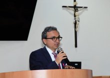 - Imagem do juiz Ely Jorge de paletó e óculos pretos falando para o público