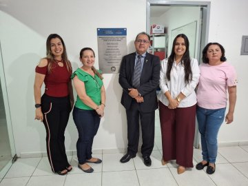 Imagem de homem branco, paletó preto; duas mulheres do lado esquerdo, uma de cabelos longos, blusa verde e calça jeans e outra de cabelos longos, blusa vermelha e calça preta. Do lado direito temos outras duas mulheres